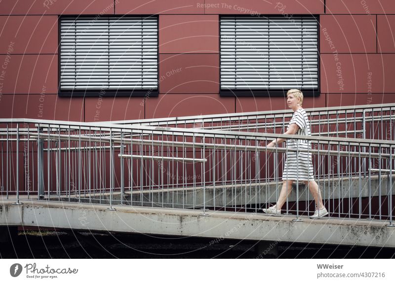 A woman in a striped dress walks through an urban world of stripes Stripe lines Woman Passer-by blinds Facade Window Town Closed staircase Ramp rail Horizontal