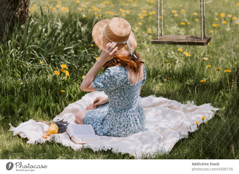 Woman on picnic blanket in nature woman summer rest straw hat meadow relax female countryside grass weekend dress leisure swing literature recreation peaceful