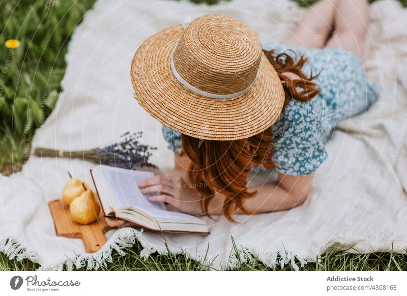 Relaxed woman with book resting in summer nature picnic relax chill straw hat weekend blanket female countryside leisure literature recreation meadow peaceful