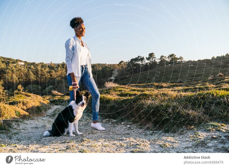 Woman with dog walking in nature woman happy pet love animal trail countryside companion female friend black african american loyal owner lifestyle ethnic