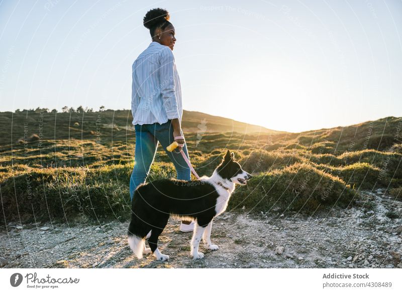 Woman with dog walking in nature woman happy pet love animal trail countryside companion female friend black african american loyal owner lifestyle ethnic