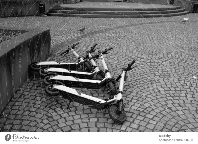 Overturned tourist e-scooters on cobblestones in downtown Frankfurt am Main, Hesse, photographed in neo-realistic black and white e-roller electric scooter