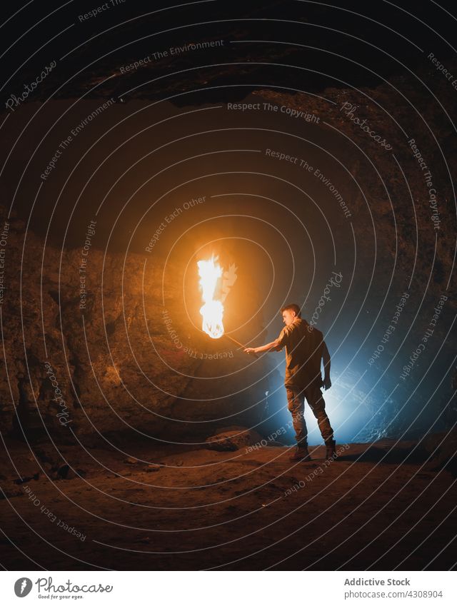 Man with burning fire in dark cave man explore speleology adventure rocky nature geology male torch stone travel tourism subterranean formation rough wild