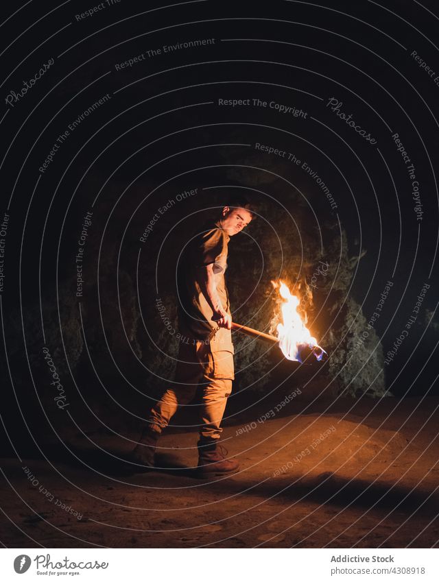 Man with burning fire in dark cave man explore speleology adventure rocky nature geology male torch stone travel tourism subterranean formation rough wild