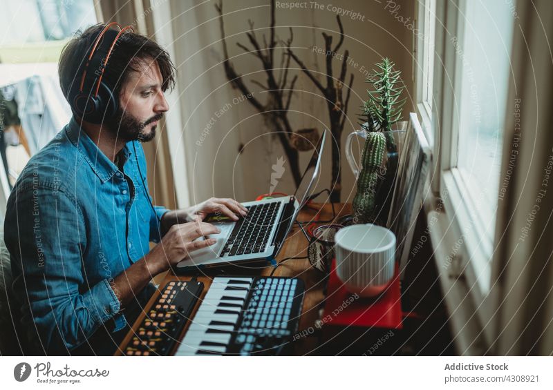 Musician using synthesizer and laptop at home musician headphones man young table studio device gadget equipment player recording room apartment leisure audio