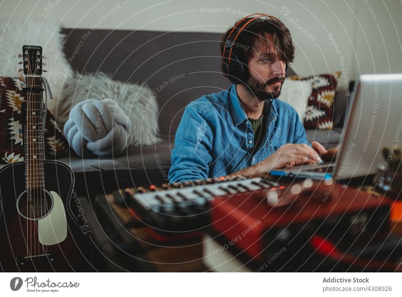 Musician using synthesizer and laptop at home musician headphones man young table studio device gadget equipment player recording room apartment leisure audio