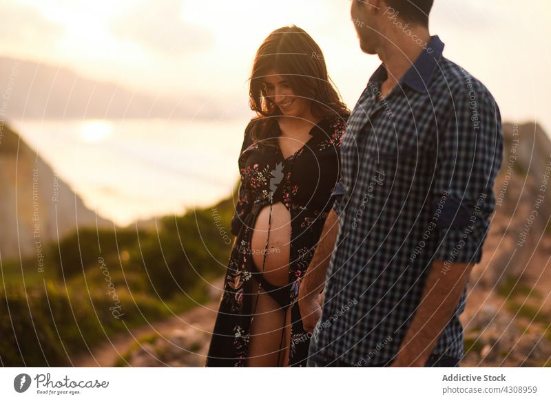 Loving young parents expecting baby on seaside couple pregnant happy love together nature belly seashore relationship romantic holding hands smile affection