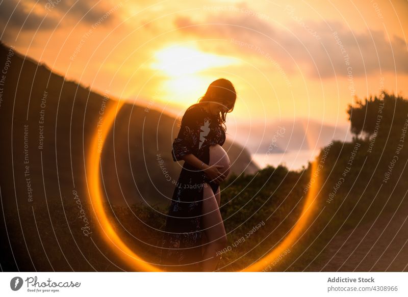 Happy pregnant woman in sunset light in nature happy belly expect love peaceful mother maternal female tummy young anticipate harmony prenatal pregnancy baby