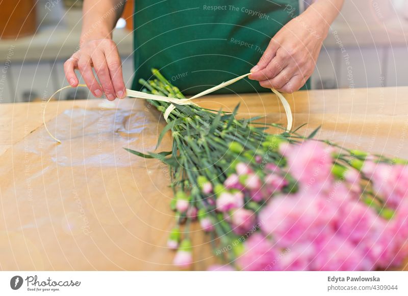 Florist at work flower flowers bunch bouquet holding people senior mature woman female employee working job occupation profession botanist blooming blossoming