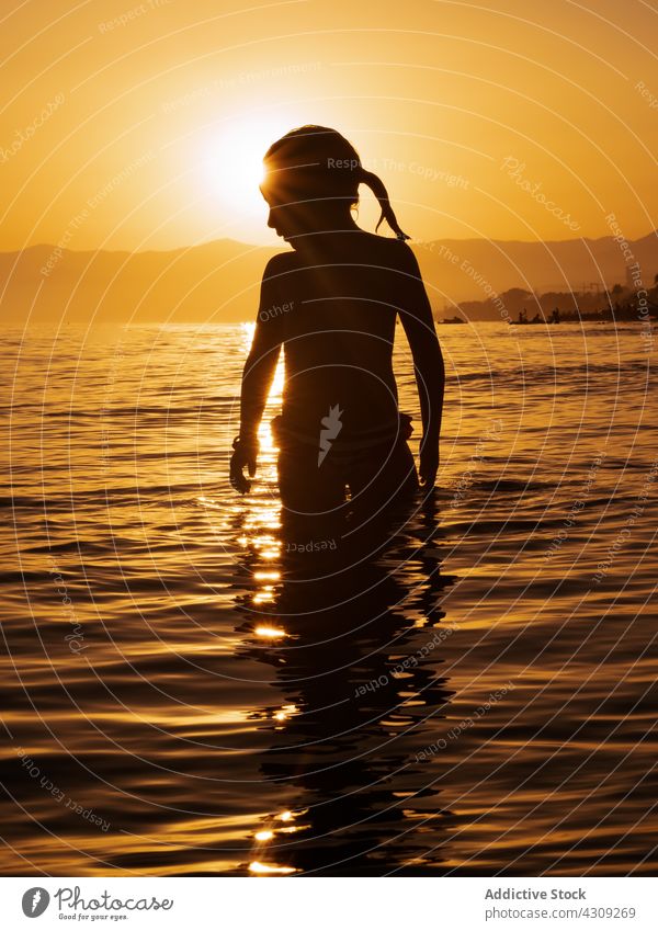 Happy kid in water at sunset sea silhouette happy girl summer sunlight nature vacation freedom leisure beach recreation enjoy child female evening activity
