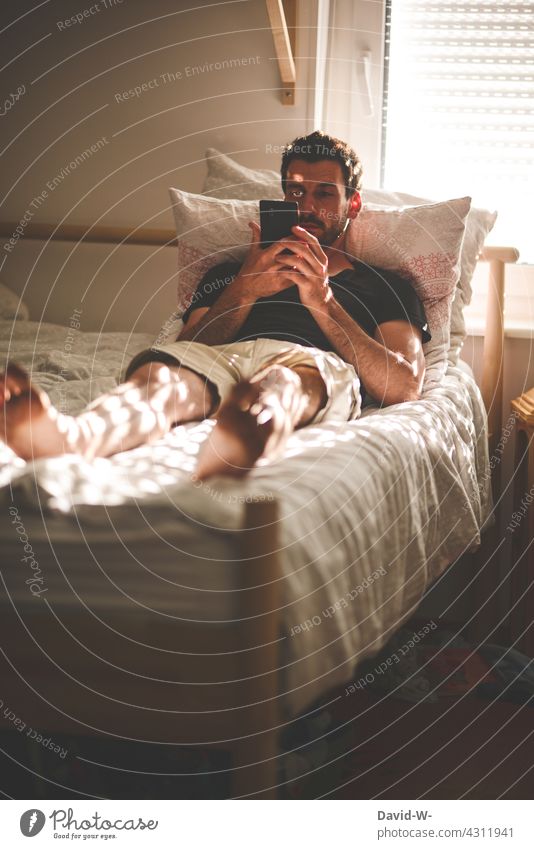 Man with mobile phone in hands in bed Cellphone Bed Reading chill news Telecommunications smartphone Communicate Lifestyle Technology rest