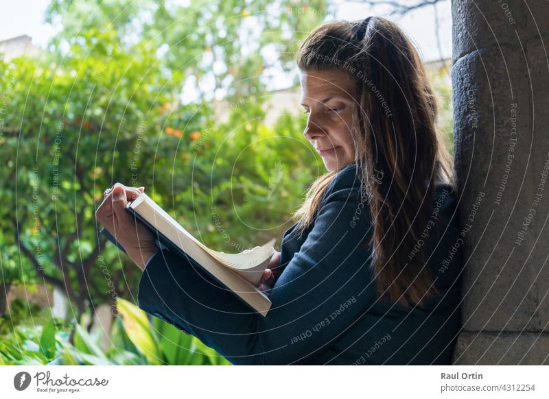 Portrait of a happy female sitting in a city park concentrated reading a book . person woman outdoor enjoying resting relaxation leisure work businesswoman