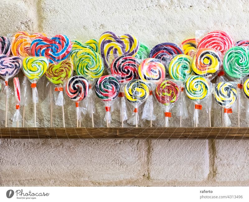 Colorful spiral lollipops on shop shelf swirl candy confectionery sweet colourful striped unhealthy isolated stick sucker red sugar white background delicious