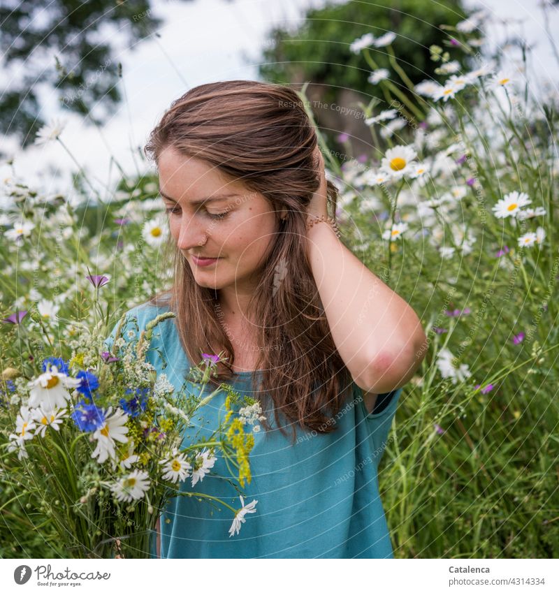 The young woman holds a bouquet of meadow flowers, in the background a flower meadow Nature flora person feminine Young woman Brunette naïve look Plant Blossom