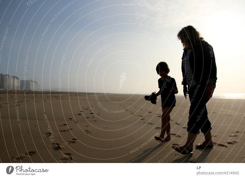contrast silhouettes of a child and adult  walking on the beach outdoor recreation Structures and shapes Education Playing Pacific Ocean ocean beach Lifestyle