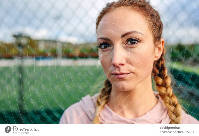 Serious young sportswoman with boxer braids looking camera serious athlete face copy space closeup defiant look natural hard woman fence active big eyelashes