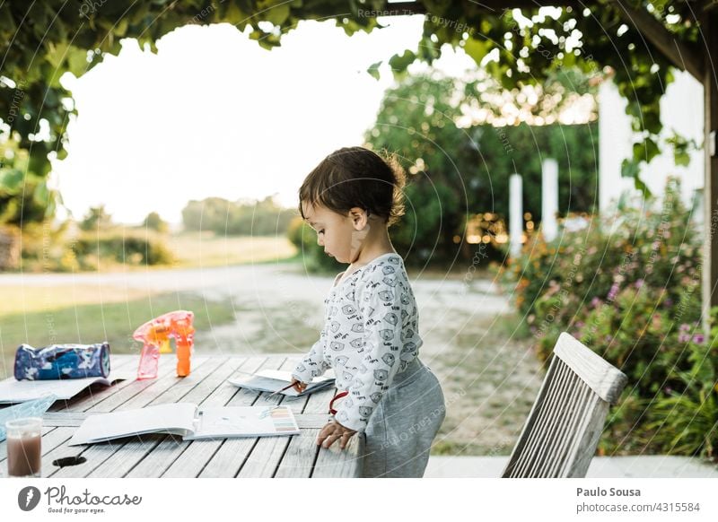 Child reading a book in the table 1 - 3 years Caucasian Day Happy Infancy Toddler Joy Colour photo Exterior shot Life Leisure and hobbies Happiness Playing Cute