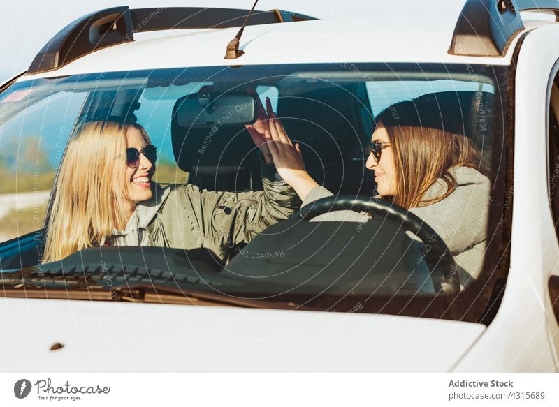 Happy women giving high five in car travel together friendship cheerful trip happy transport freedom countryside gesture vehicle nature support laugh smile road