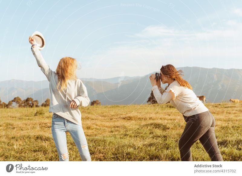 Women having fun in nature and taking photos women best friend take photo moment memory girlfriend together summer hat mountain style photo camera enjoy travel