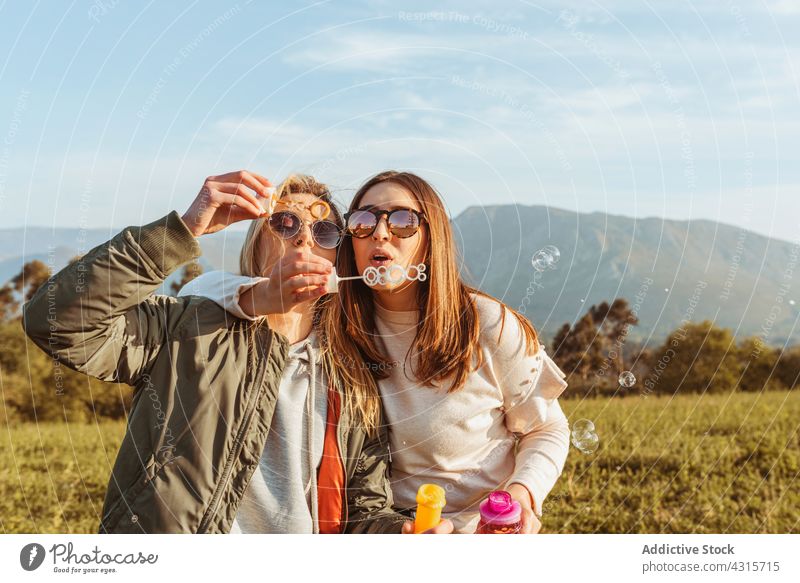 Happy women with soap bubbles in nature fun blow together best friend friendship happy summer sunglasses meadow rest leisure carefree girlfriend relax field