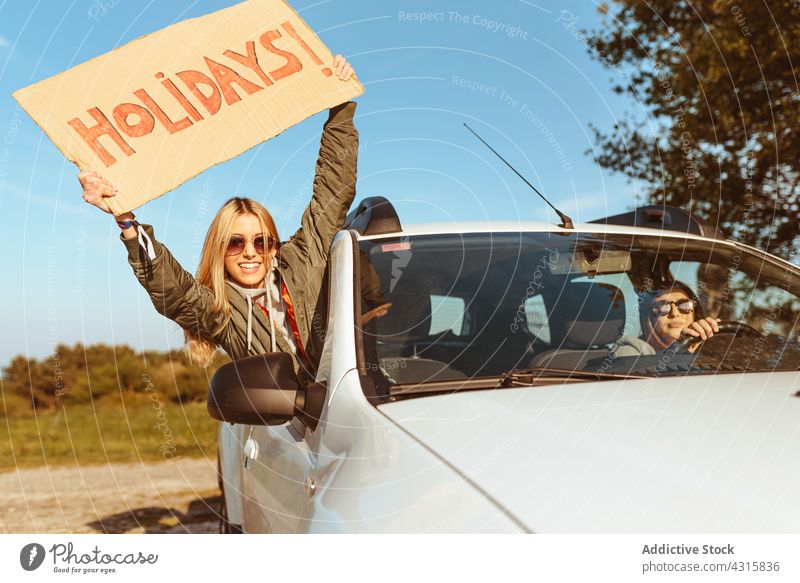 Women with signboard Holidays riding in car women girlfriend holidays fun road trip together happy cheerful window freedom rest enjoy vacation journey vehicle