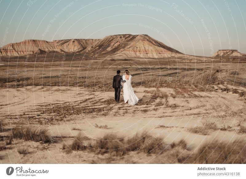 Anonymous couple walking in desert on wedding day newlywed plain mountain together man woman navarra spain bardenas reales love natural park reserve romantic