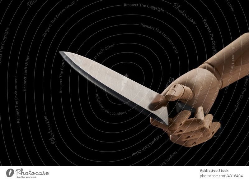 Crop wooden hand with sharp knife in studio violent concept criminal weapon danger tool shape scary fear crime steel murder threat pressure creepy force metal