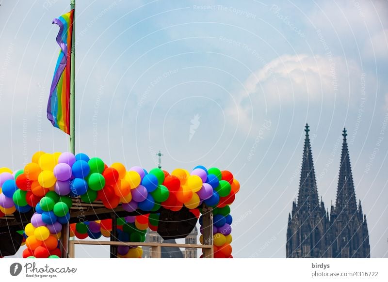 many colourful balloons in rainbow colours and a rainbow flag in front of the Cologne Cathedral Prismatic colors Catholic Church Gender justice