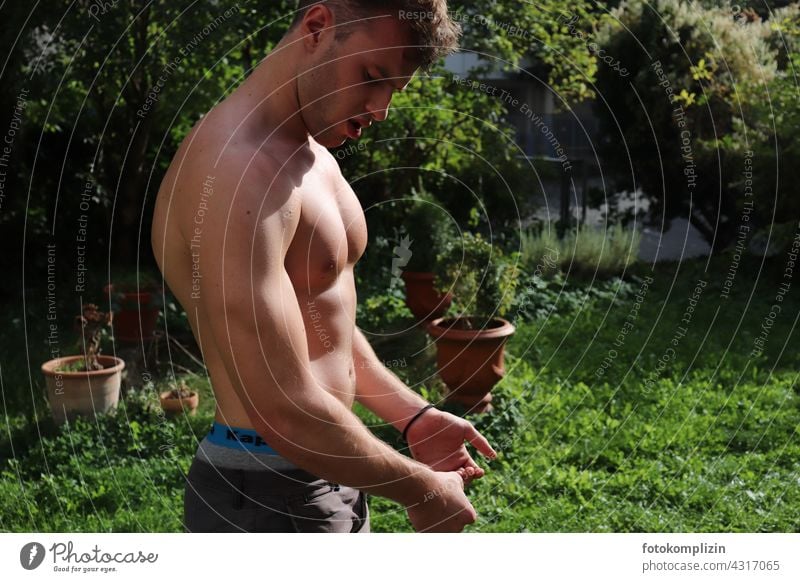 young man flexes his muscles in garden Muscular Body Force Fitness workout Man Upper body Musculature Garden Attractive Naked Body building strength Athletic