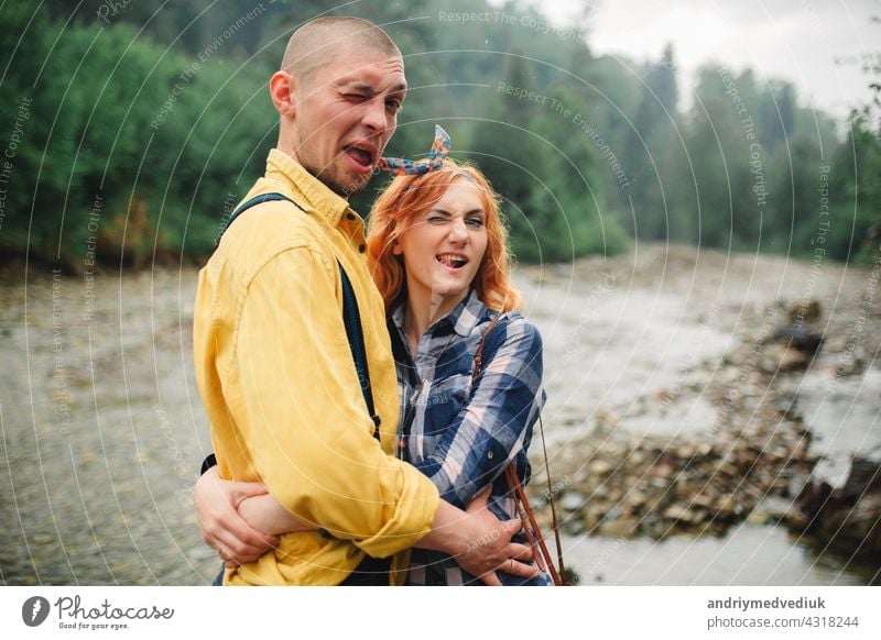 Playful happy handsome couple having while walking in woods. tourists in the mountains. Adventure in nature concept. caucasian playful piggyback outdoors