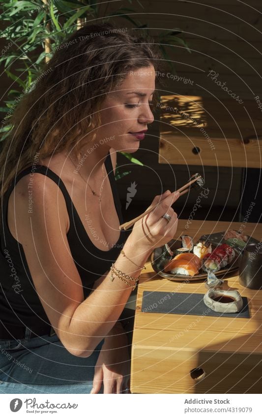Woman eating sushi in Asian restaurant woman roll set asian food asian cuisine delicious tasty female table oriental yummy meal chopstick gourmet fresh