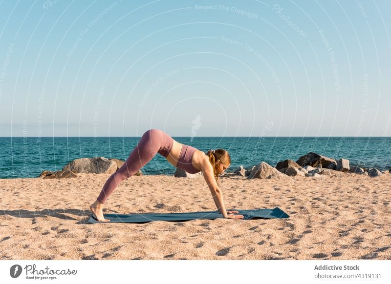 Woman doing yoga in Downward Facing Dog pose on beach woman practice harmony downward facing dog pose stretch flexible asana sea female sand healthy position