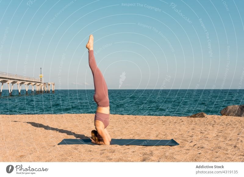Woman practicing yoga in Headstand on beach woman headstand pose balance salamba sirsasana zen seashore practice female wellness harmony mat healthy tranquil