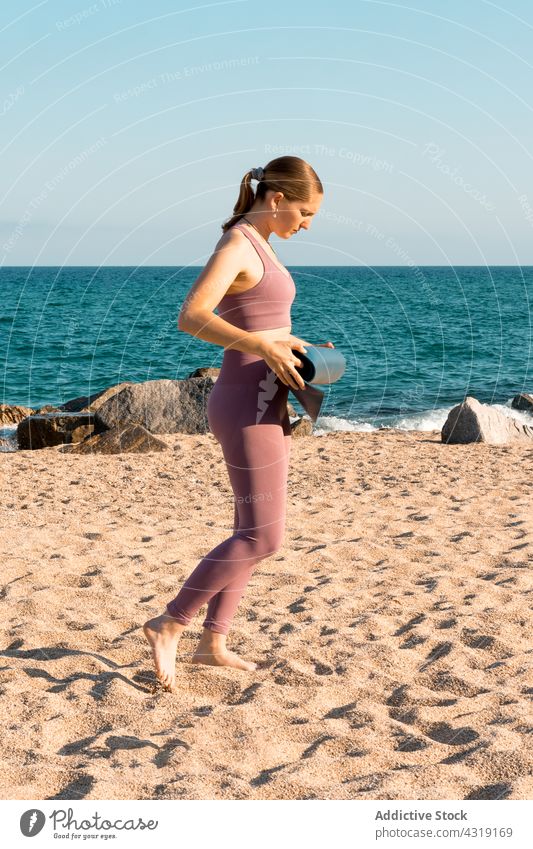 Woman preparing for yoga practice on beach woman prepare sand mat activity sea wellness female sportswear activewear lifestyle nature healthy young wellbeing