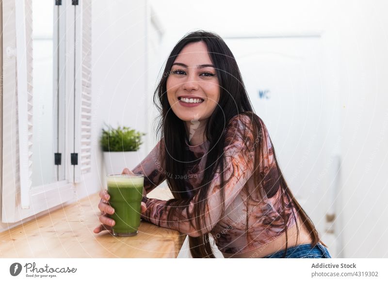 Content woman enjoying green beverage in bar chill weekend counter content cheerful relax smile female modern glad young positive happy rest delight style