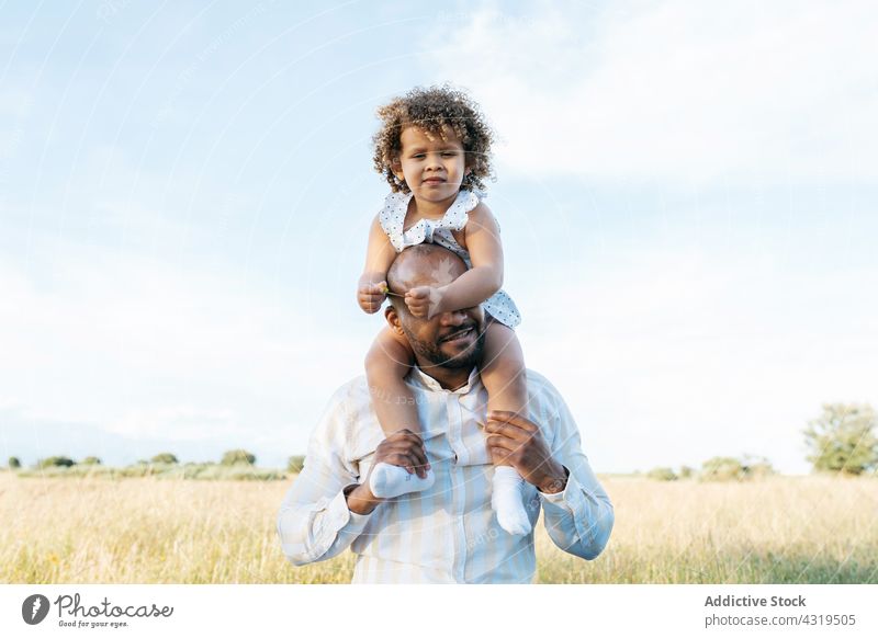 Black father and daughter having fun in summer field on shoulders play ride together child playful game black african american ethnic cover eyes happy kid girl