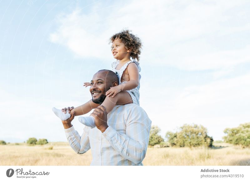 Delighted black father and daughter having fun in summer field on shoulders play ride together child playful game african american ethnic happy kid cheerful