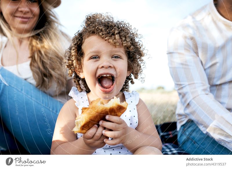 Happy multiethnic family having picnic in nature eat child together enjoy summer multiracial diverse girl black african american cheerful happy relax smile kid