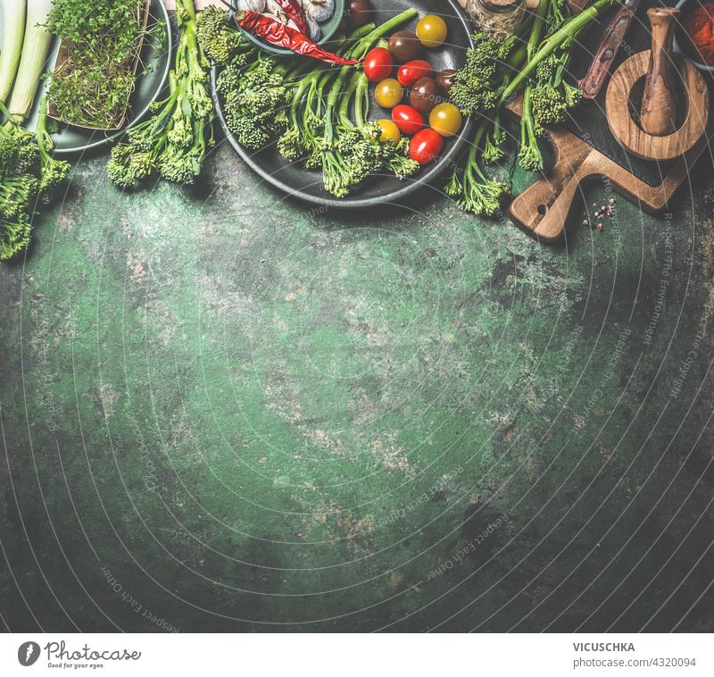 Food background  with a variety of green vegetables, wild broccoli, tomatoes and other healthy ingredients for vegan cuisine. Border. Top view food border