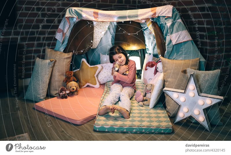Girl hugging stuffed doll playing in a diy tent at home lovely girl closed eyes snuggle smile sweet charming child cute teddy kid female barefoot toy bear