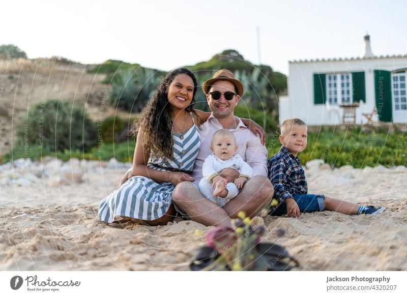 The family with two small boys sitting and posing on the beach portrait together son toddler baby portugal algarve piggyback recreation caucasian sunset walking