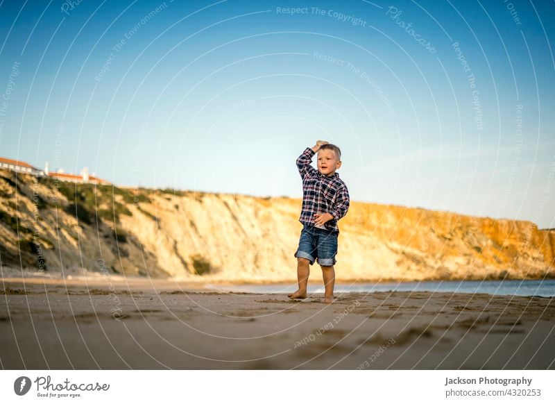 Small boy throwing stones on the beach by the sunset play toddler copy space sagres portugal barefoot son horizontal baby sunny run seaside summertime playful