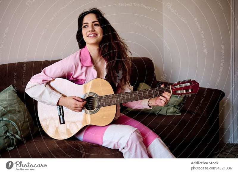 Smiling woman playing guitar at home acoustic music musician instrument melody guitarist enjoy female sound song happy rehearsal hobby smile perform cheerful