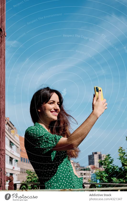 Content woman taking selfie on balcony smartphone self portrait smile summer charming cheerful enjoy female device gadget take photo using happy mobile young