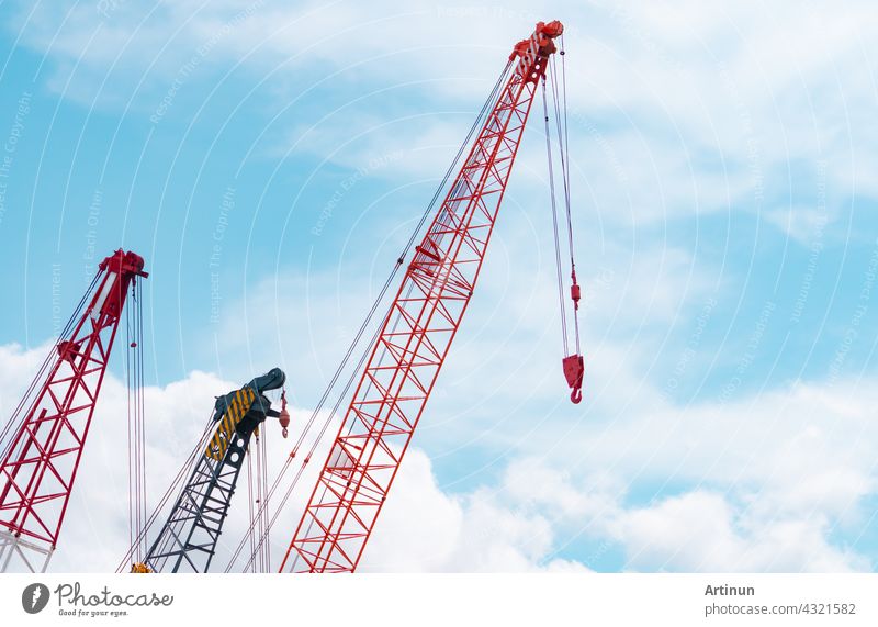 Crawler crane against blue sky and white clouds. Real estate industry. Red crawler crane use reel lift up equipment in construction site. Crane for rent. Crane dealership for construction business.