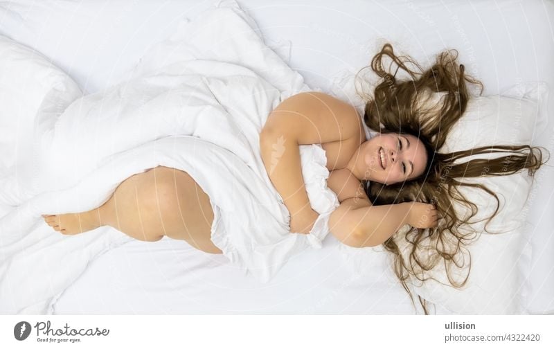 Fat plump woman with long hair, beaming with joy, view from above, copy space happiness relaxing wake up waking sexy bed caucasian happy attractive resting