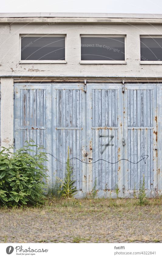 7 | Number and arrow on weathered rolling gate Goal Rolling door Weathered Wood Blue Closed Deserted Entrance Exterior shot overgrown Warehouse Storage Garage