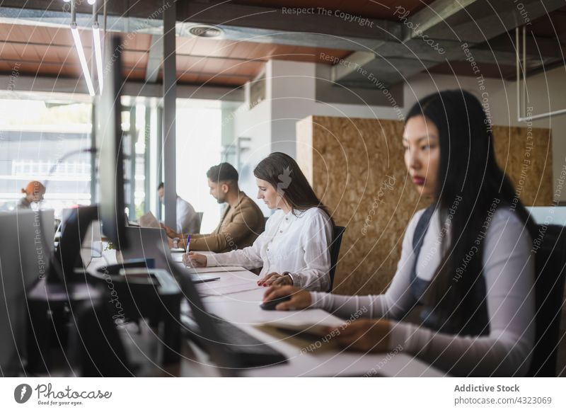 Diverse colleagues working at table in office coworker group project space busy workplace together multiethnic multiracial diverse asian business laptop
