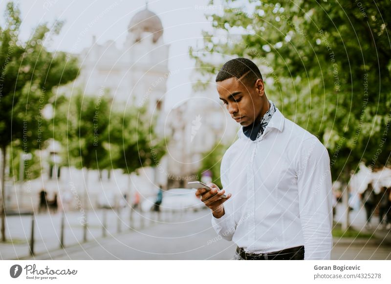 Young African American businessman using a mobile phone while waitng for a taxi on a street american black building cab call calling causal city communication