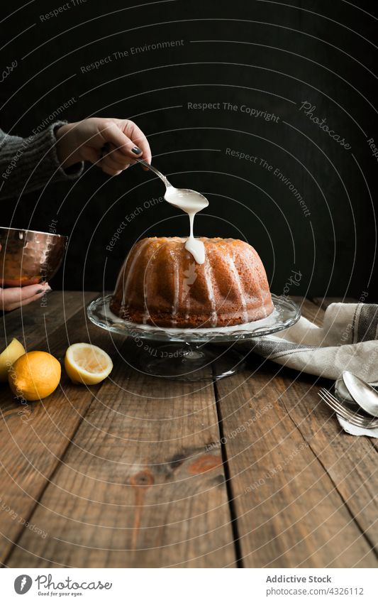 Crop hand icing a lemon sponge cake homemade dessert food pastry birthday delicious baked bakery lady apron pound cake wooden table whole woman circle fingers